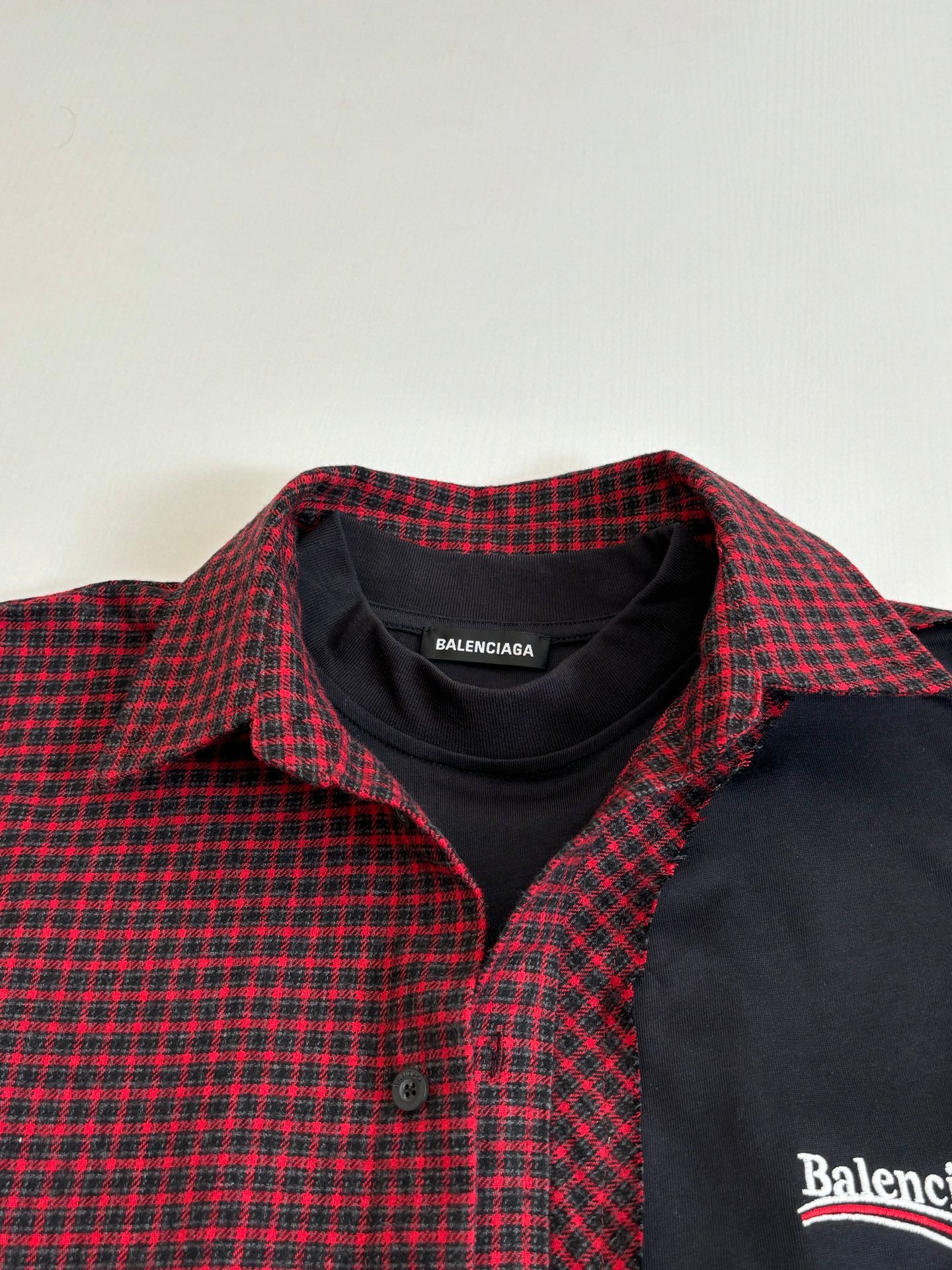 Balenciaga long-sleeve shirt collar closeup; red-and-black check with black placket