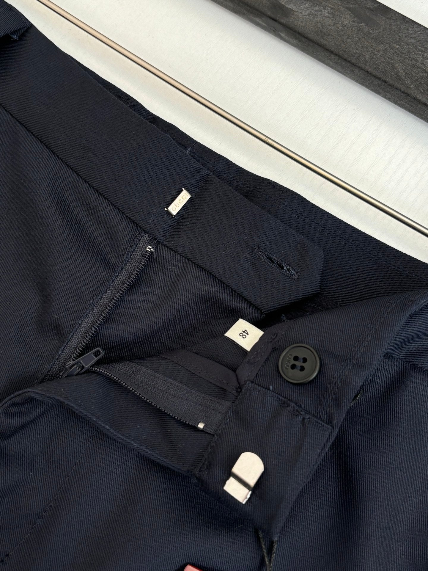 Gucci navy pants waistband close-up with zipper, button, and belt loops