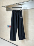 Black Balenciaga track pants on hanger, elastic waistband and tapered legs