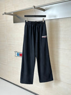 Black Balenciaga track pants on hanger, elastic waistband and tapered legs