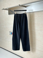 Black Balenciaga track pants with wide legs and elastic waistband, hanging
