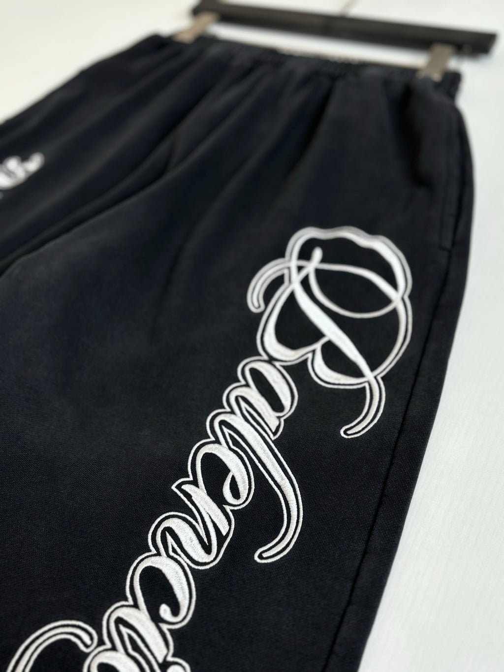 Black Balenciaga track pants with large white script logo on one leg