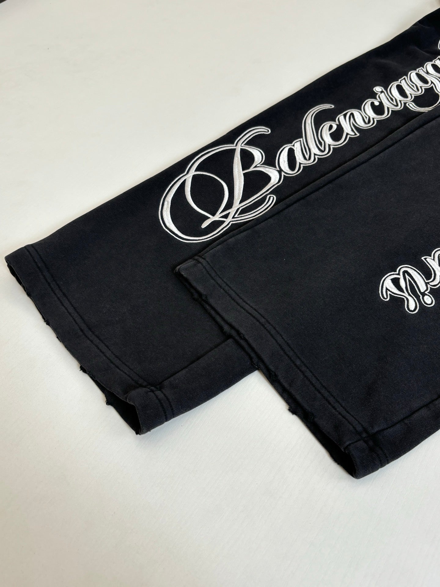 Black Balenciaga track pants with white script logo on waistband and cuff