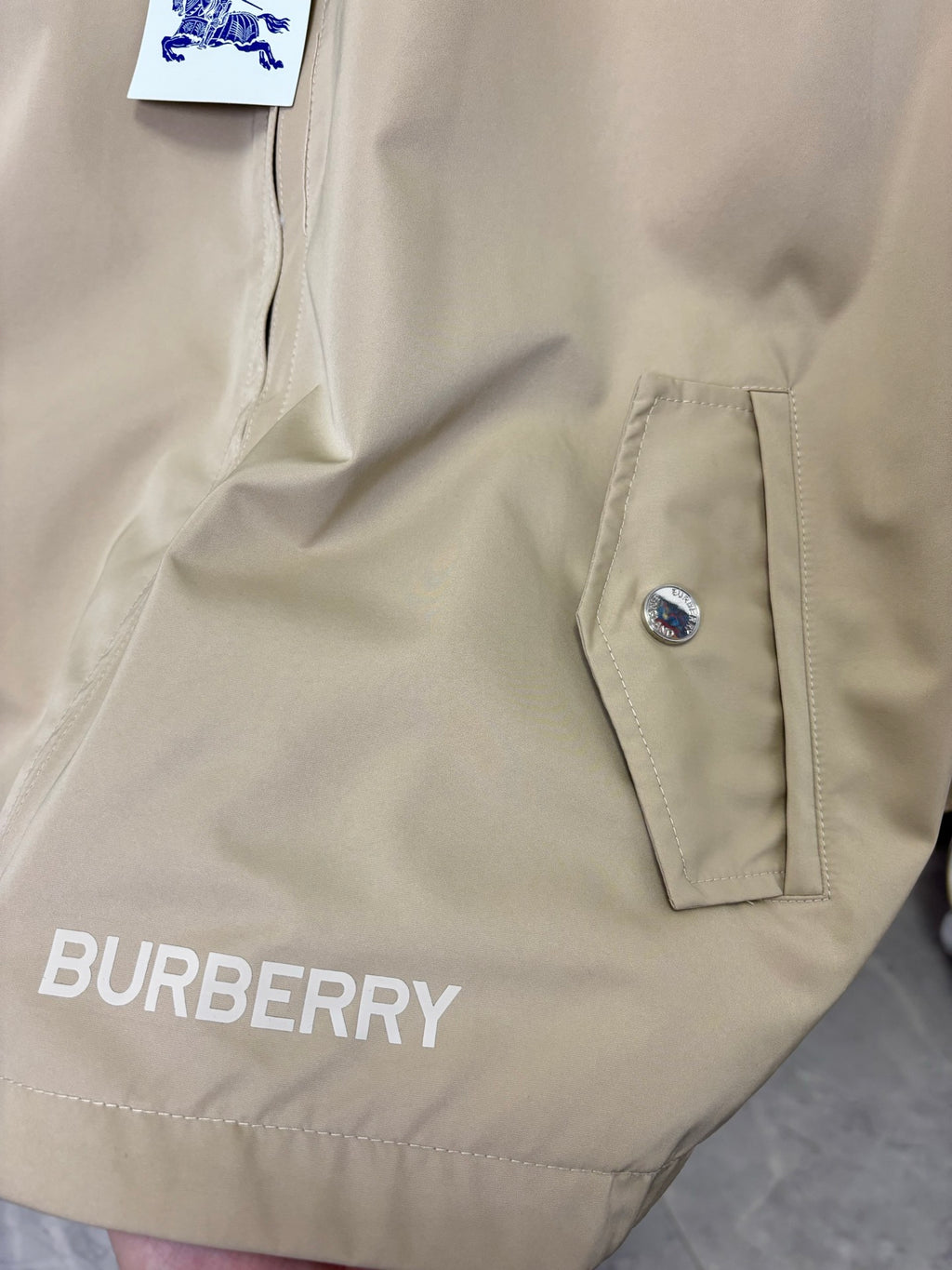 Beige jacket with snap cuff tabs and stitched chest patch
