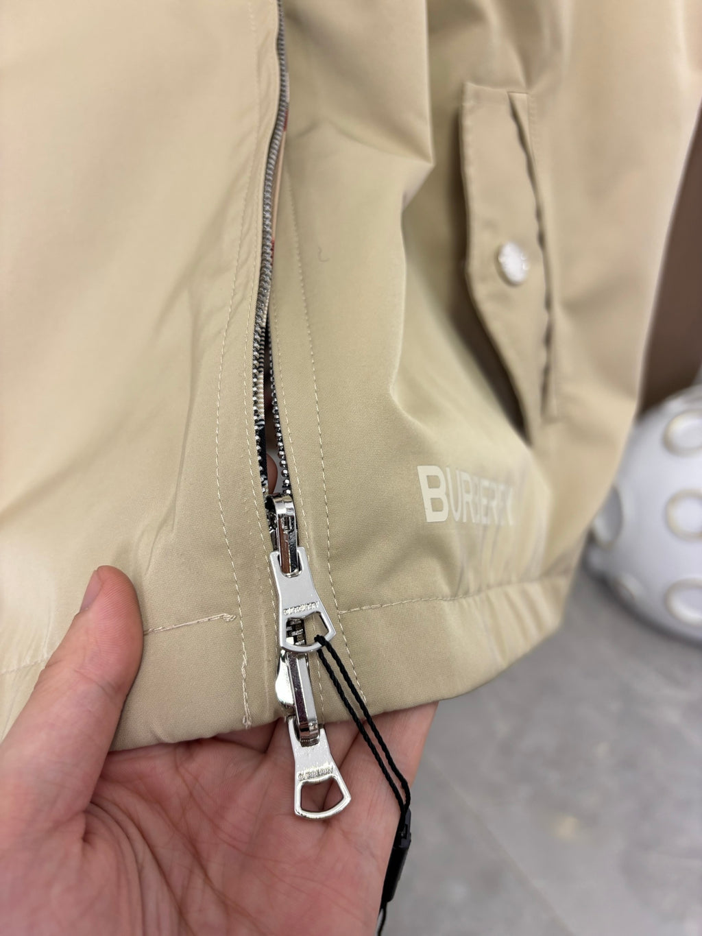 Beige jacket front zipper with metal pulls and inner striped tape