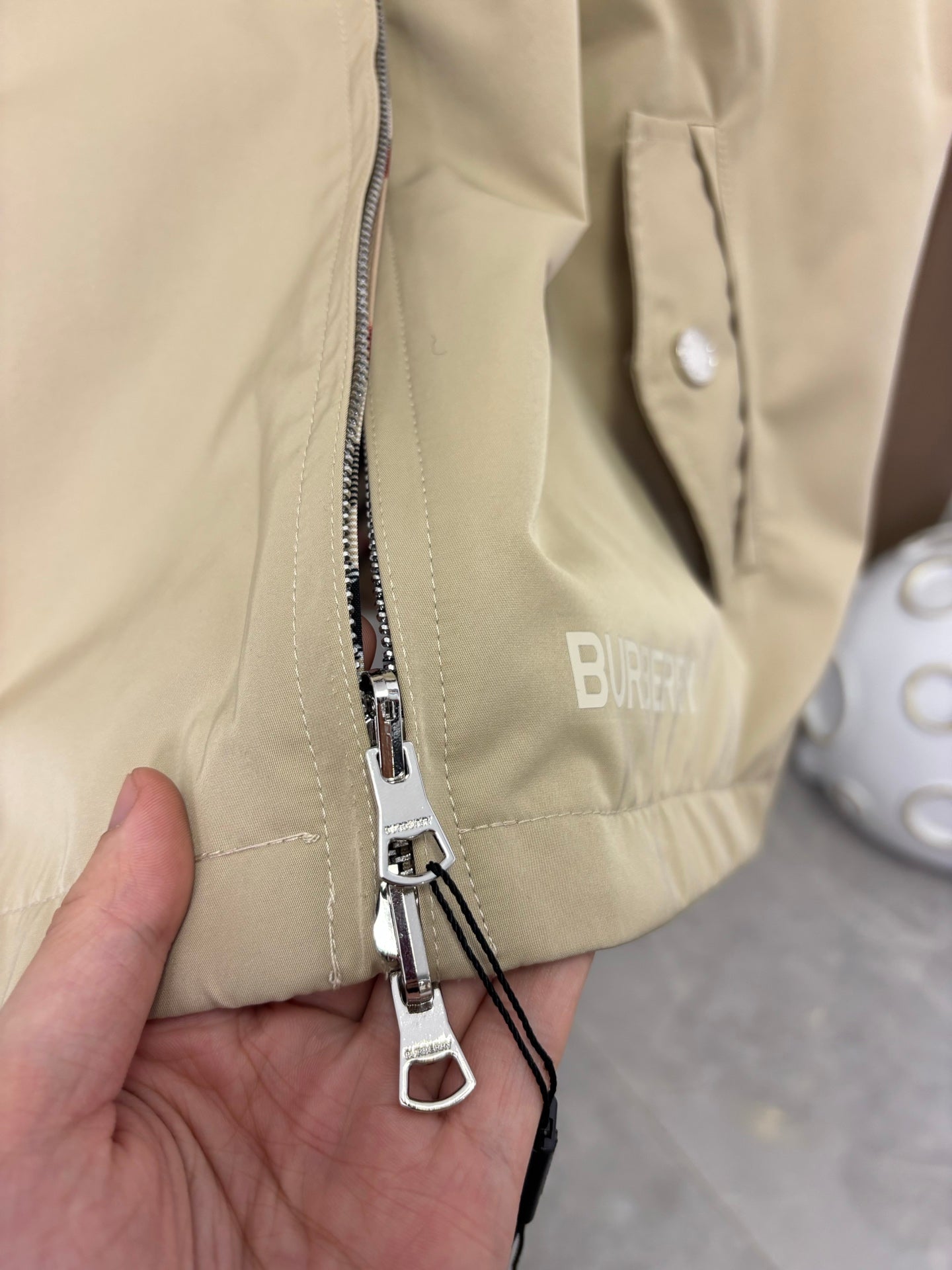 Beige jacket front zipper with metal pulls and inner striped tape