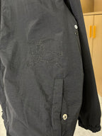 Dark jacket close-up with embroidered crest on chest and snap cuff button