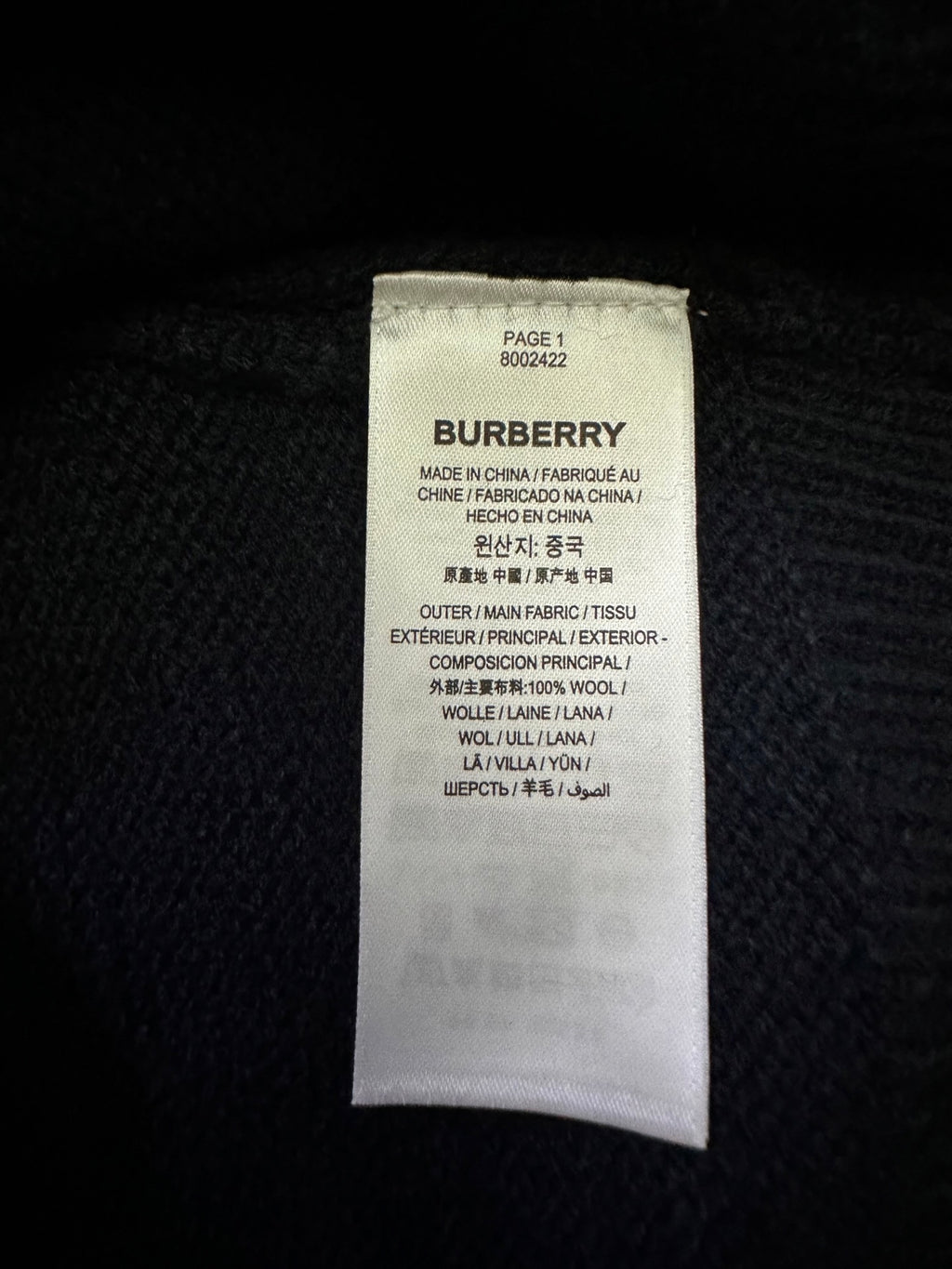 Inside label on a dark knit sweater showing Burberry and fabric details