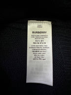 Inside label on a dark knit sweater showing Burberry and fabric details