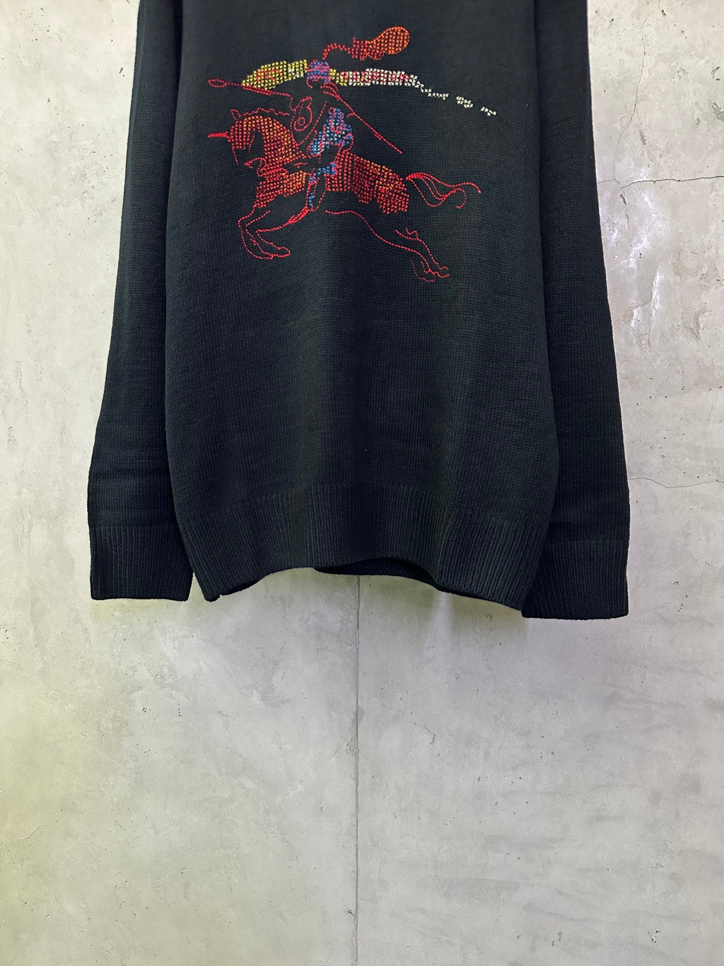 Dark navy knit sweater with large colorful horse rider graphic on the front