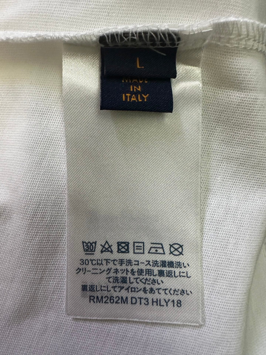 Inside care label and size tag on white T-shirt fabric