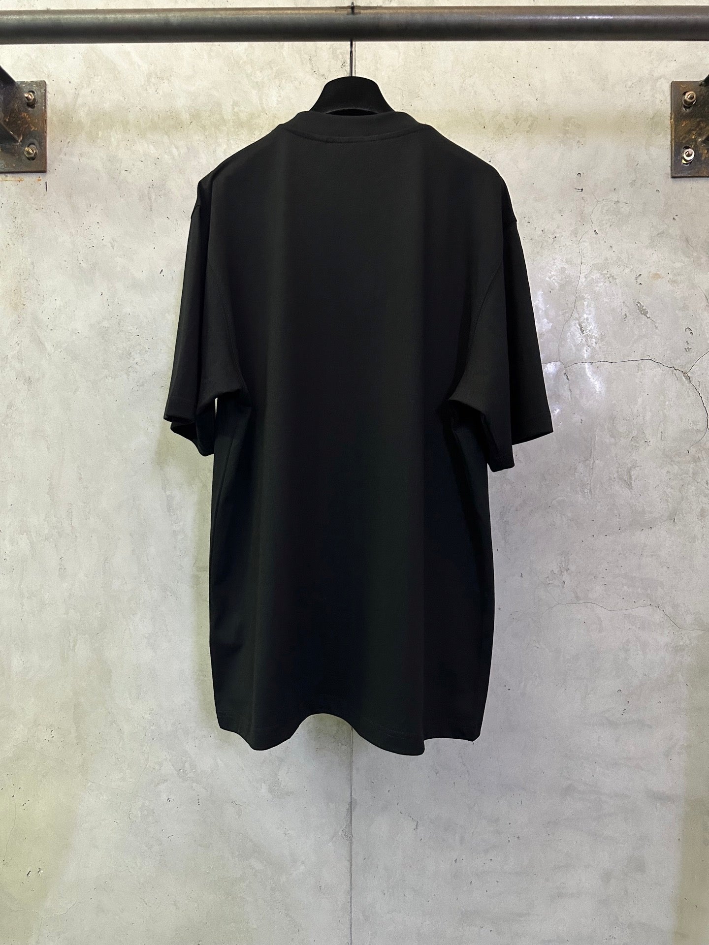 Black crewneck short-sleeve T-shirt, back view with curved hem