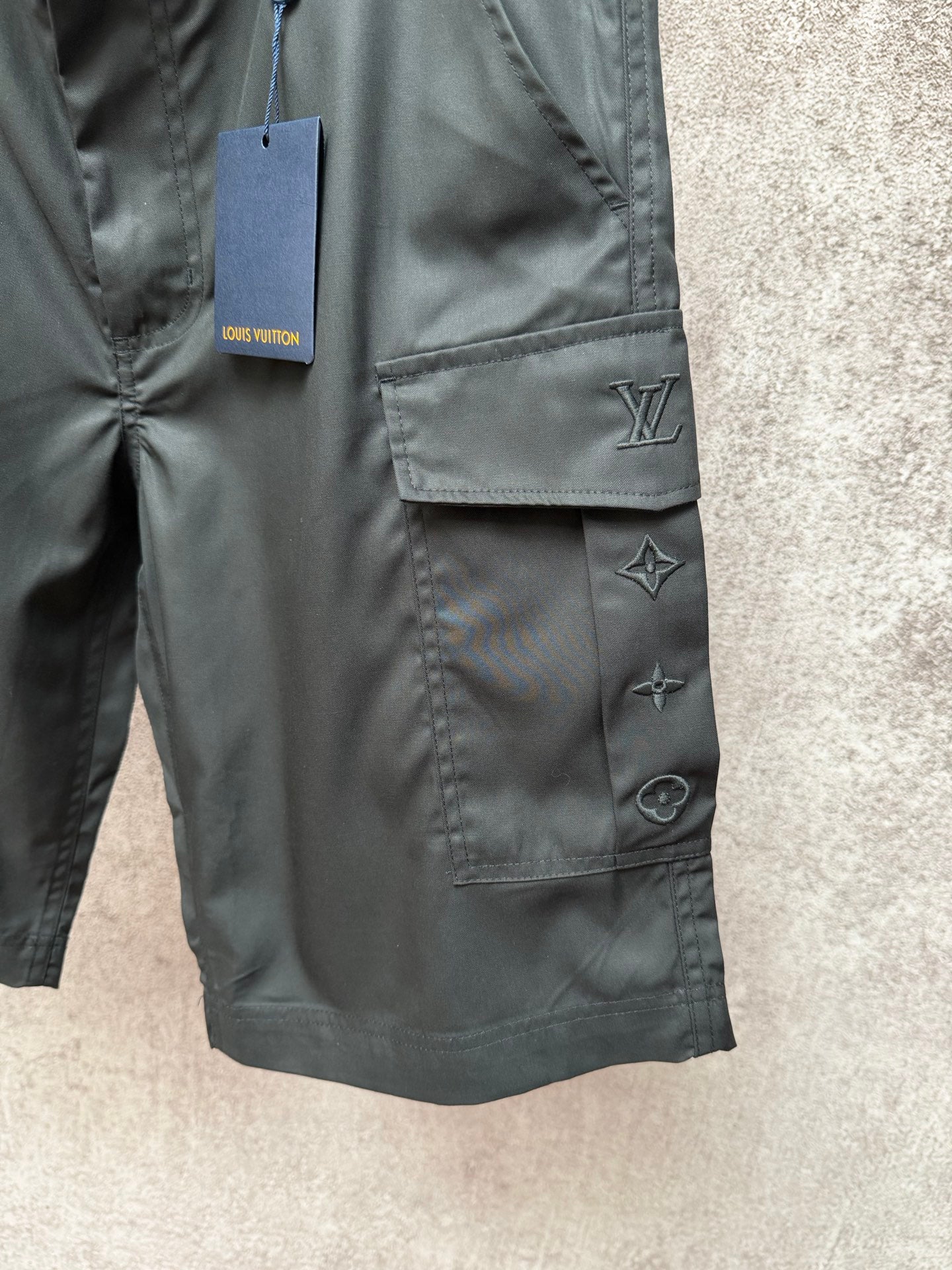 Cargo shorts pocket close-up with Louis Vuitton logo and star appliques