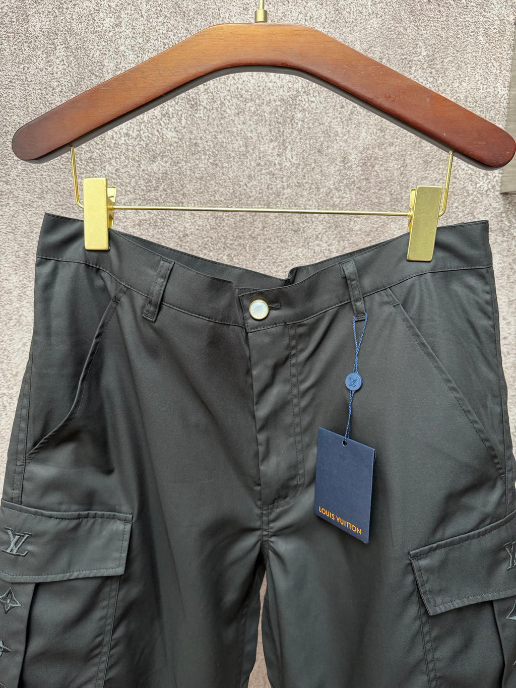 Black cargo shorts with button waist, hanging tags, and Louis Vuitton logos