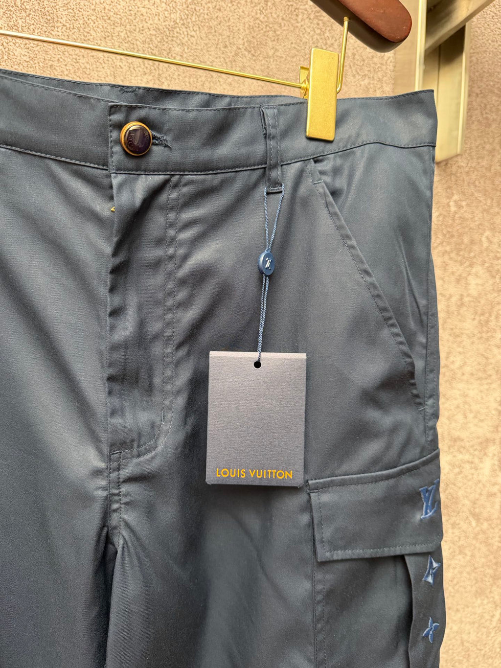 Dark blue cargo shorts waistband with button closure and Louis Vuitton hang tag