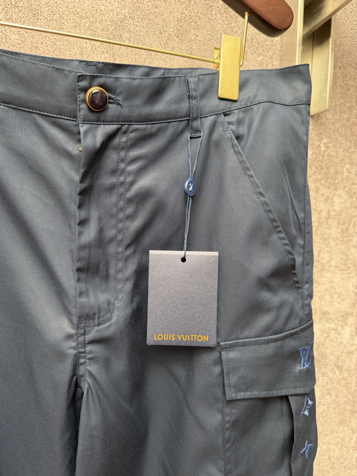 Dark blue cargo shorts waistband with button closure and Louis Vuitton hang tag