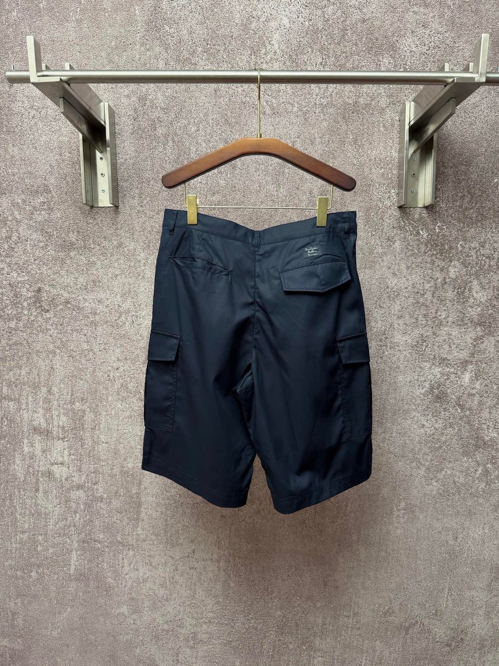 Dark blue cargo shorts with back pockets and belt loops, hanging on a hanger