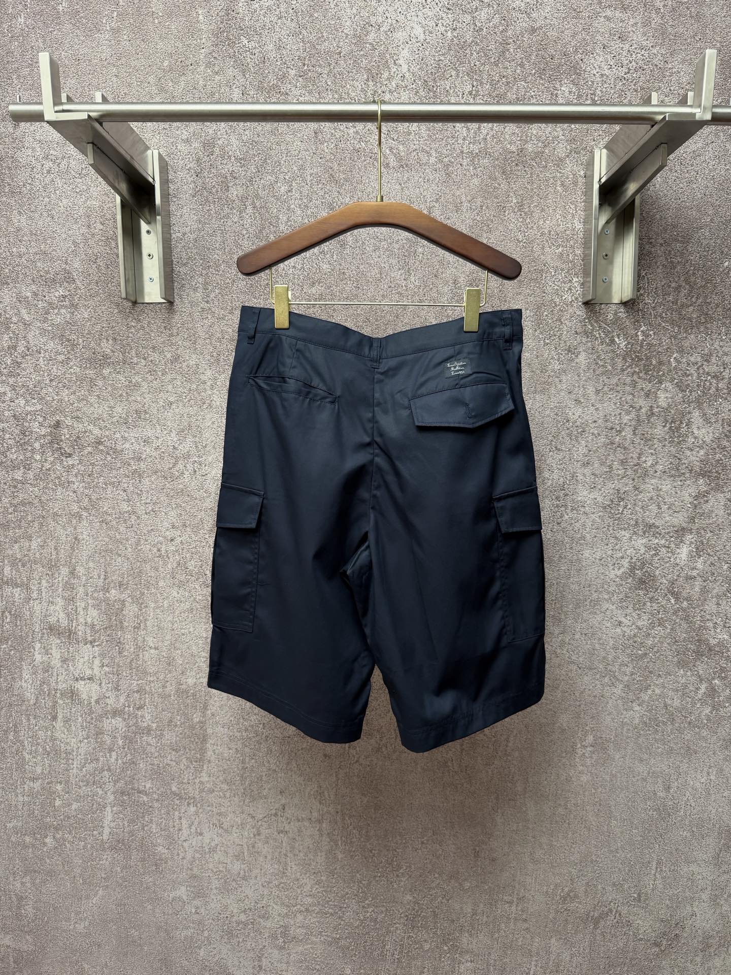 Dark blue cargo shorts with back pockets and belt loops, hanging on a hanger