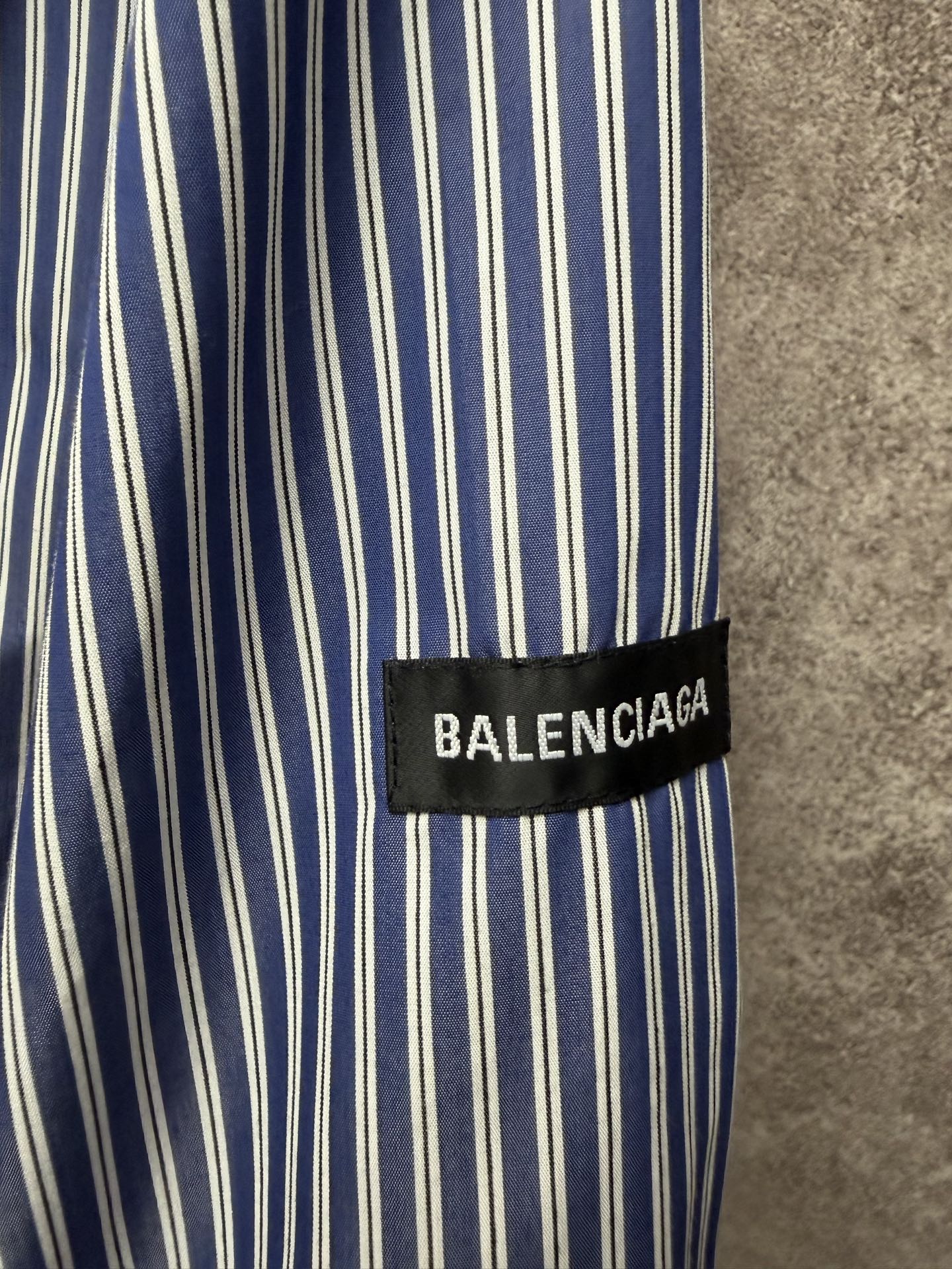 Striped shirt fabric with vertical blue-and-white lines, BALENCIAGA logo cuff label.