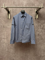 Long-sleeve button-up shirt with vertical blue-and-white stripes, button front, chest pocket.