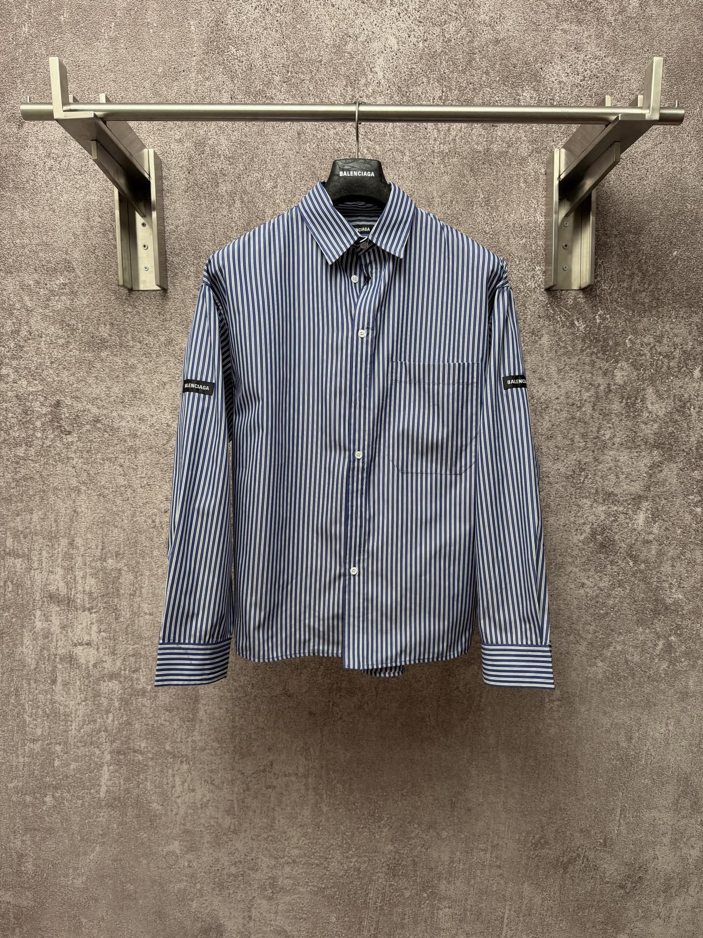 Long-sleeve button-up shirt with vertical blue-and-white stripes, button front, chest pocket.