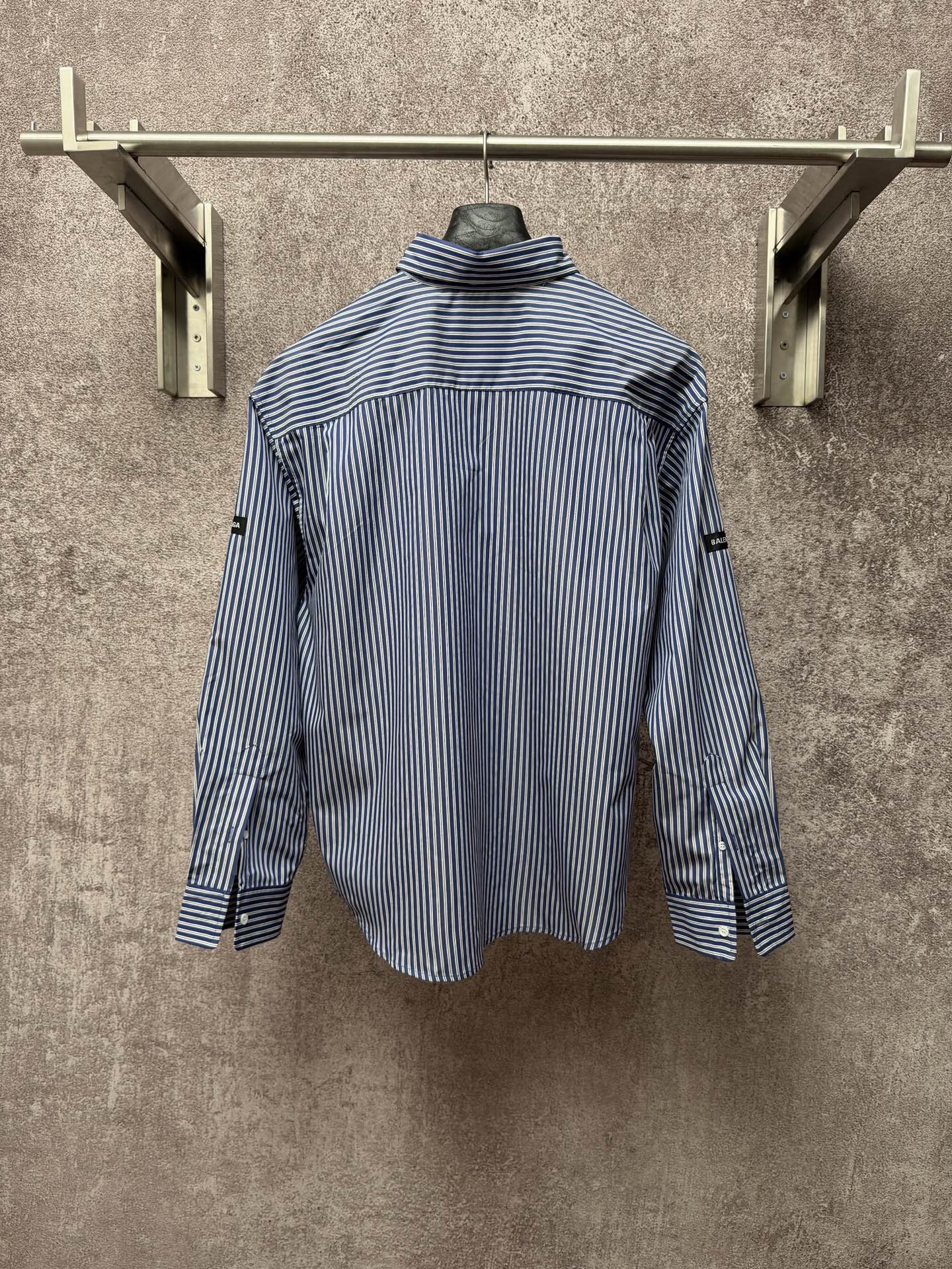 Long-sleeve button-up shirt with vertical blue-and-white stripes, standing collar, back view.