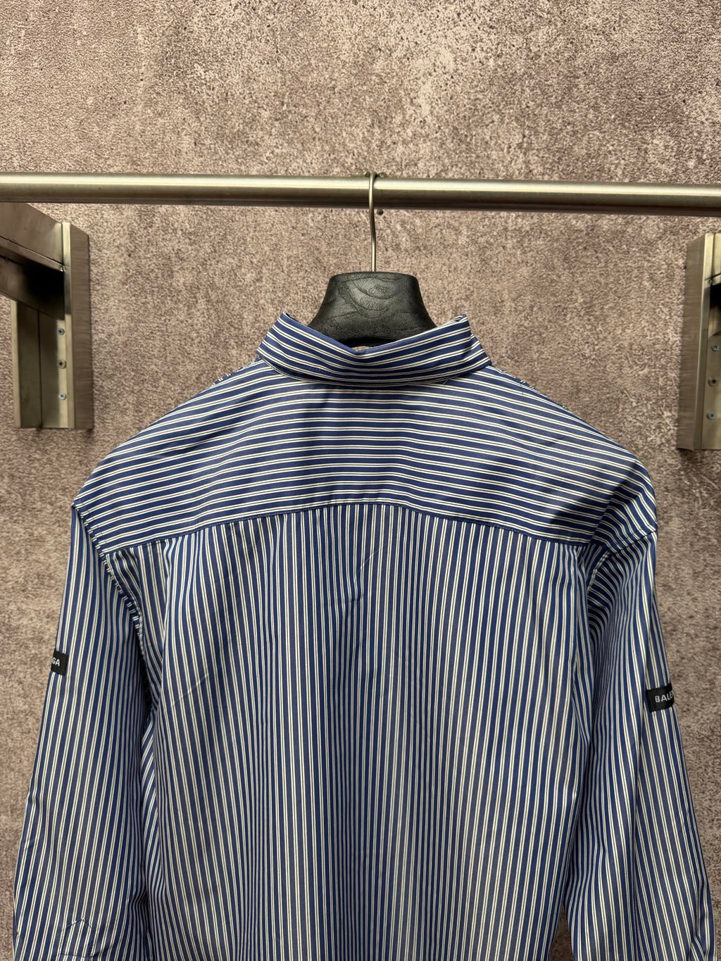 Long-sleeve button-up shirt with vertical blue-and-white stripes, raised collar, back view.