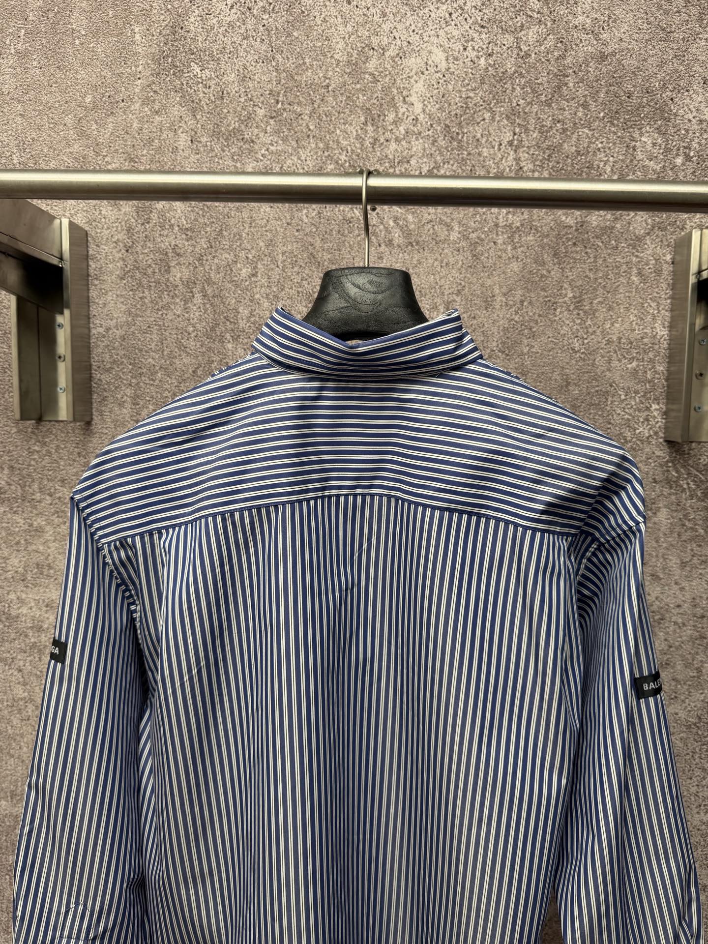 Long-sleeve button-up shirt with vertical blue-and-white stripes, raised collar, back view.