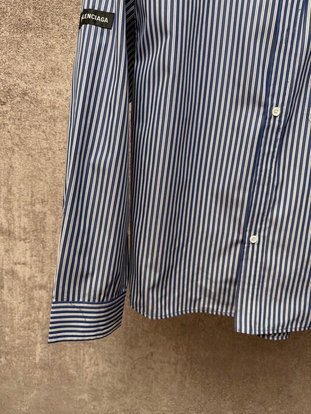 Long-sleeve striped button-up shirt sleeve with banded cuff and vertical blue-and-white stripes.