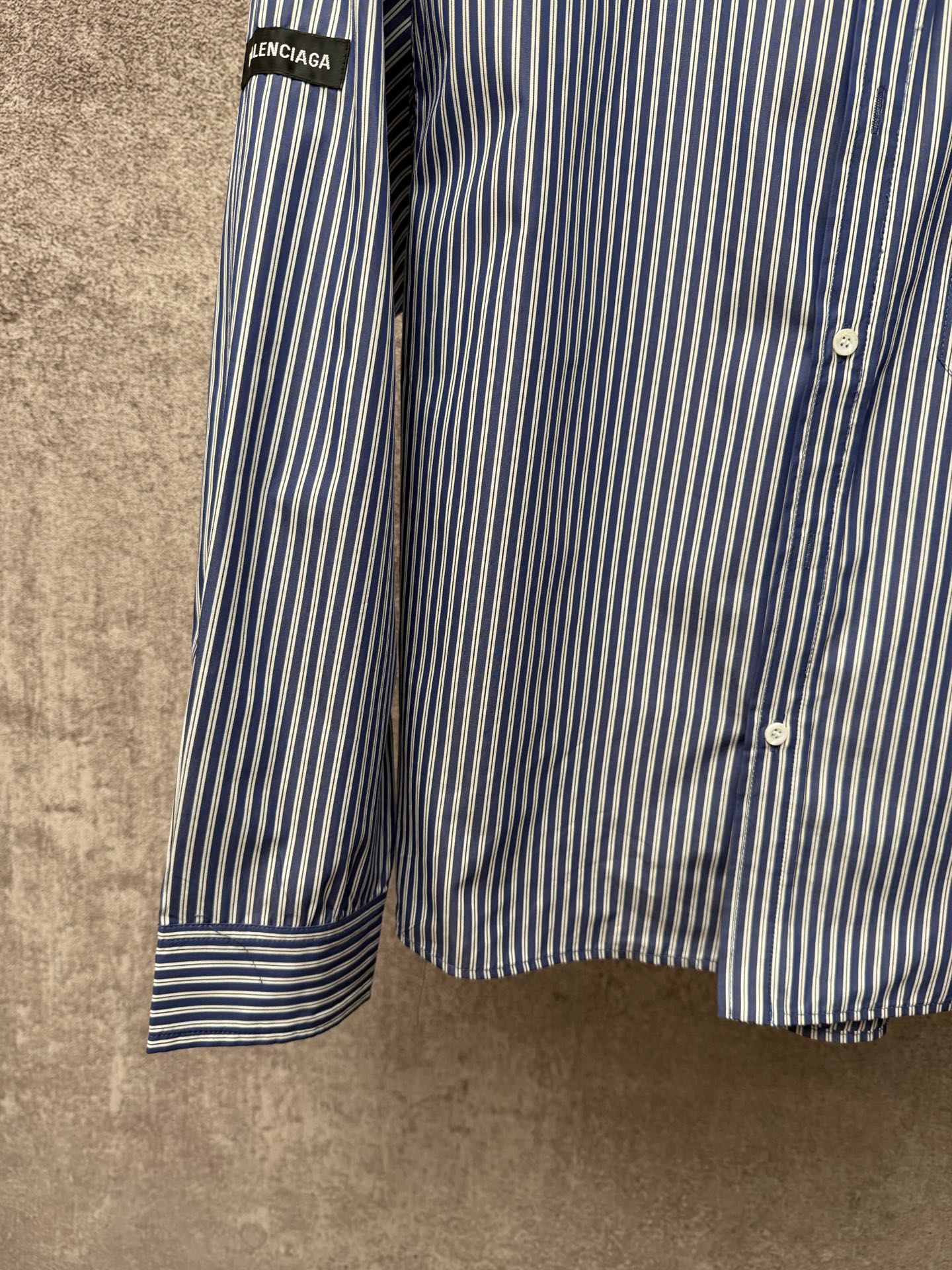 Long-sleeve striped button-up shirt sleeve with banded cuff and vertical blue-and-white stripes.