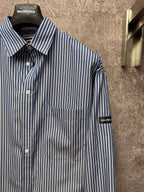 Long-sleeve striped button-up shirt with spread collar, chest pocket, logo sleeve patches.