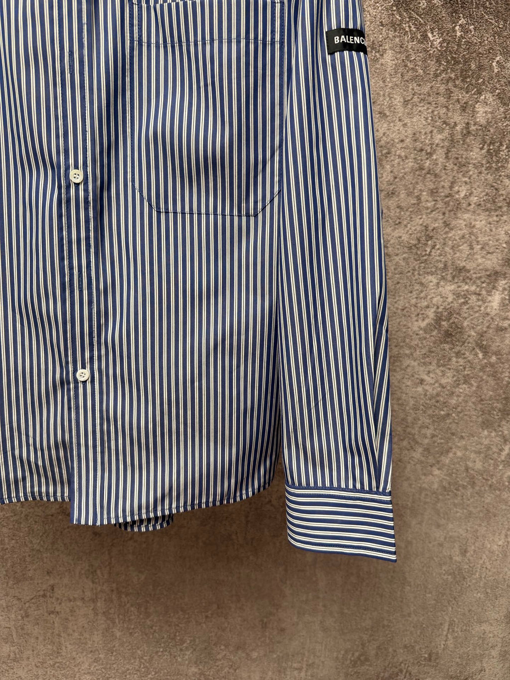 Striped button-up shirt hem and cuff, vertical blue-and-white stripes with banded cuff.