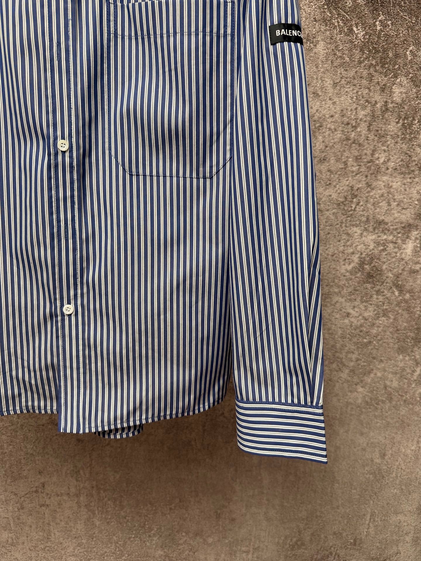 Striped button-up shirt hem and cuff, vertical blue-and-white stripes with banded cuff.