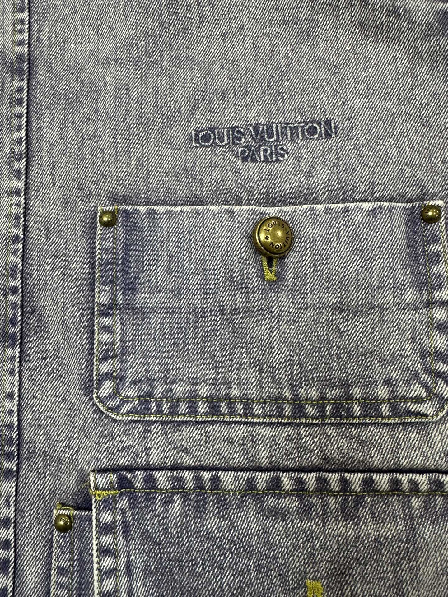 Light blue denim jacket chest pocket with gold-tone button and Louis Vuitton Paris