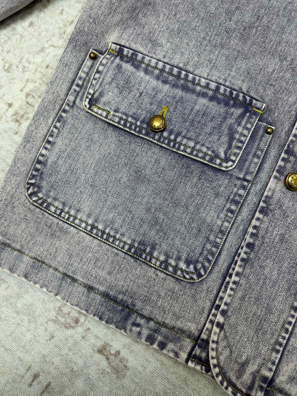 Denim jacket interior patch pocket close-up with gold snap button trim