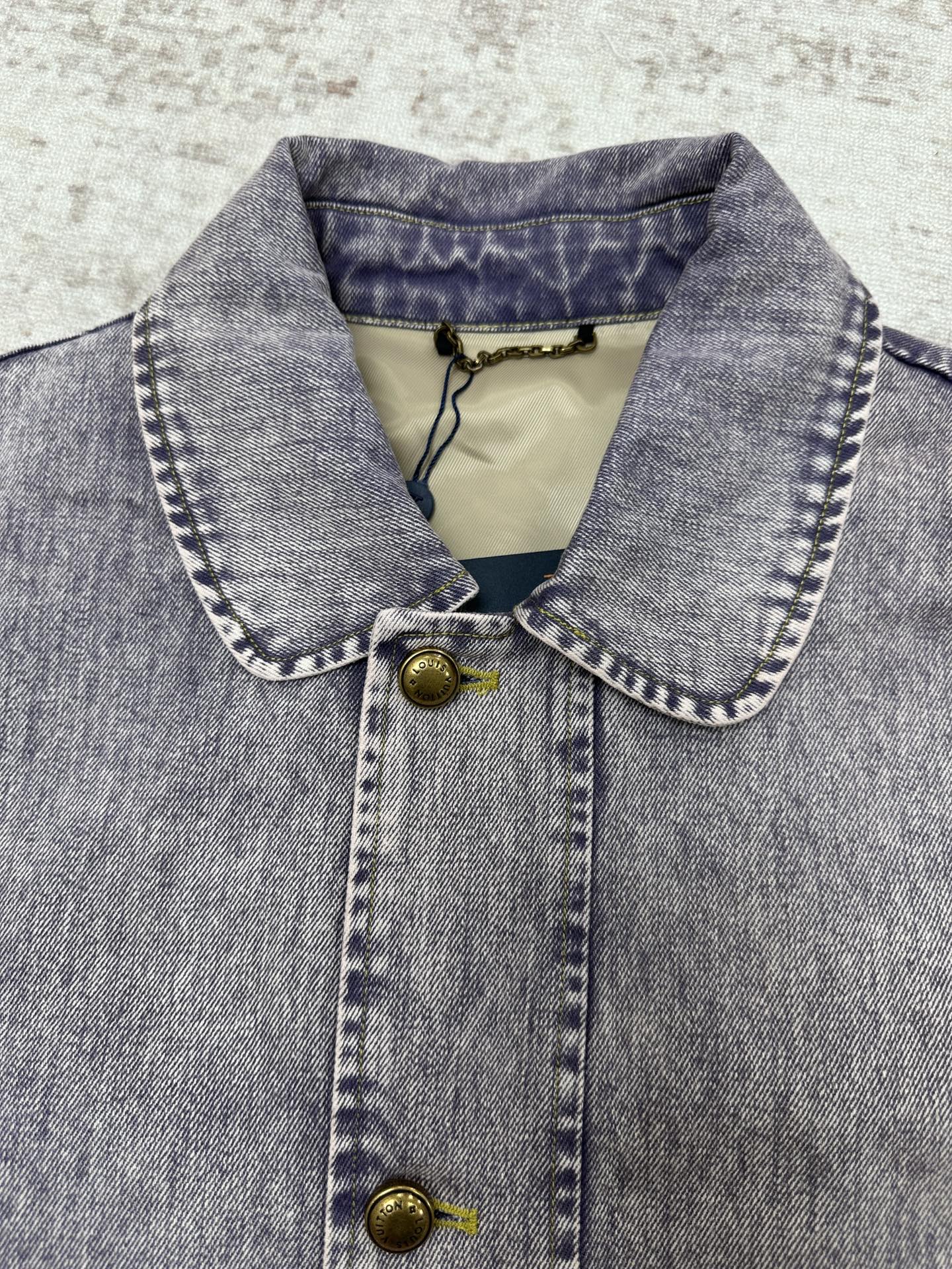 Denim jacket neckline close-up with contrast collar, button placket and gold hardware