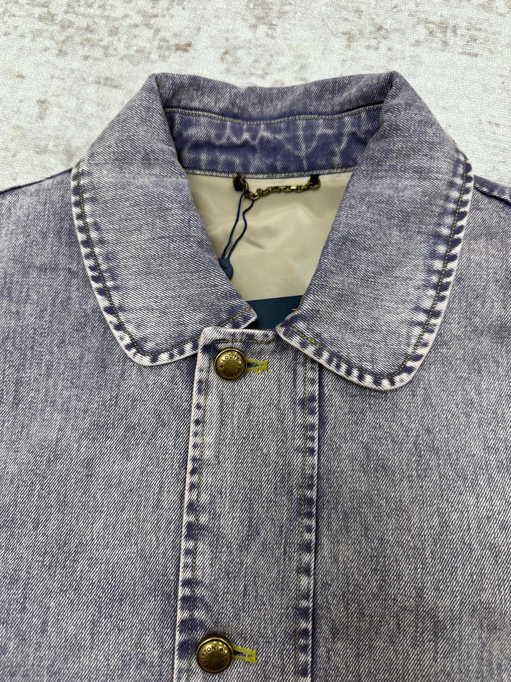 Light blue denim jacket collar with snap buttons and stitched trim