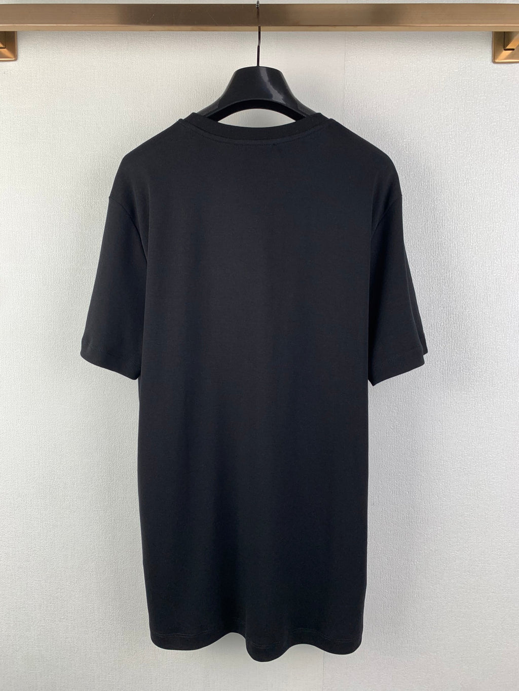 Back view of dark T-shirt with short sleeves and crew neckline.