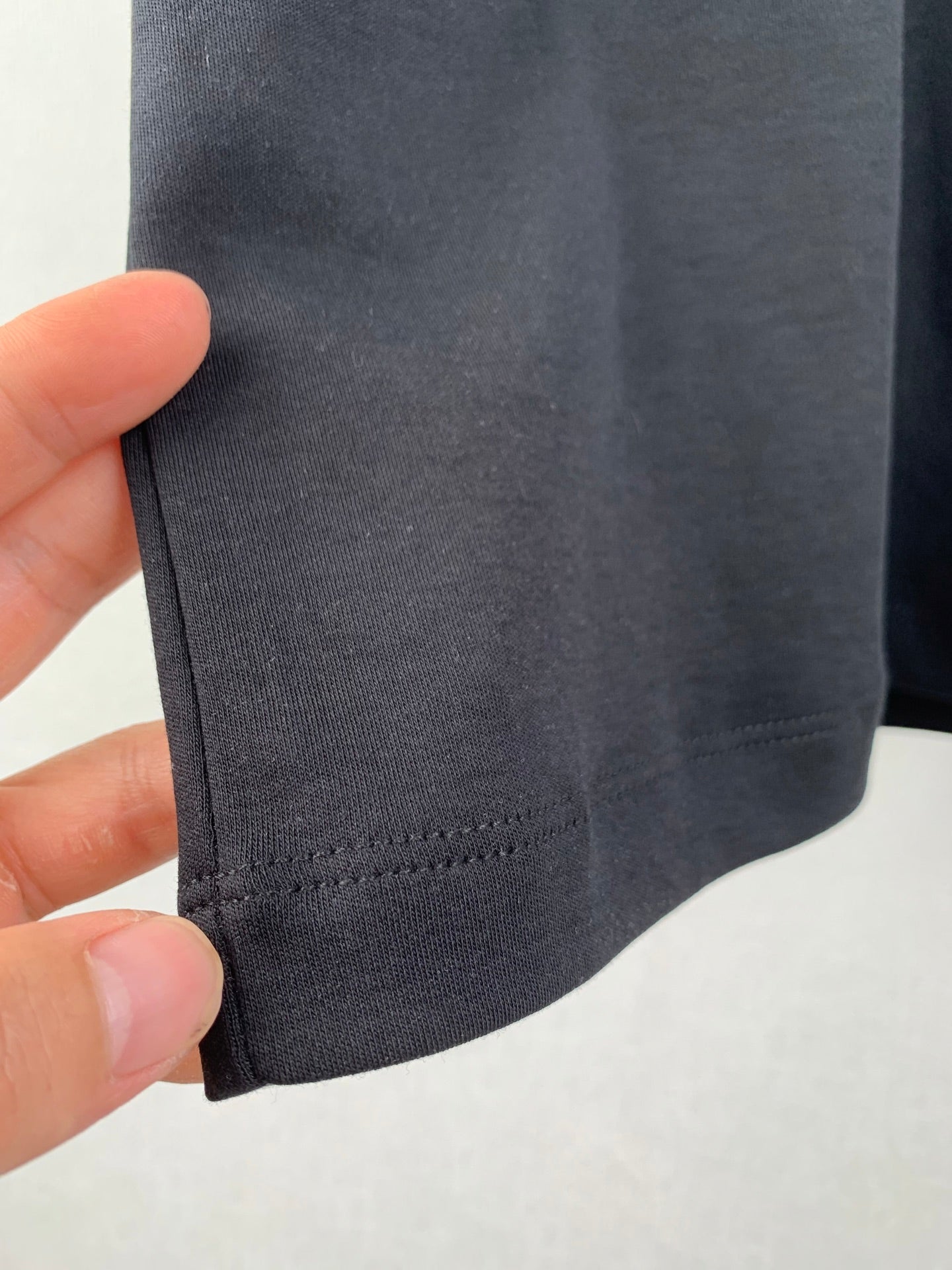 Close-up of dark T-shirt sleeve hem stitching.