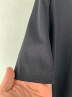 Dark T-shirt hem with visible stitching and short sleeve cuff seam.
