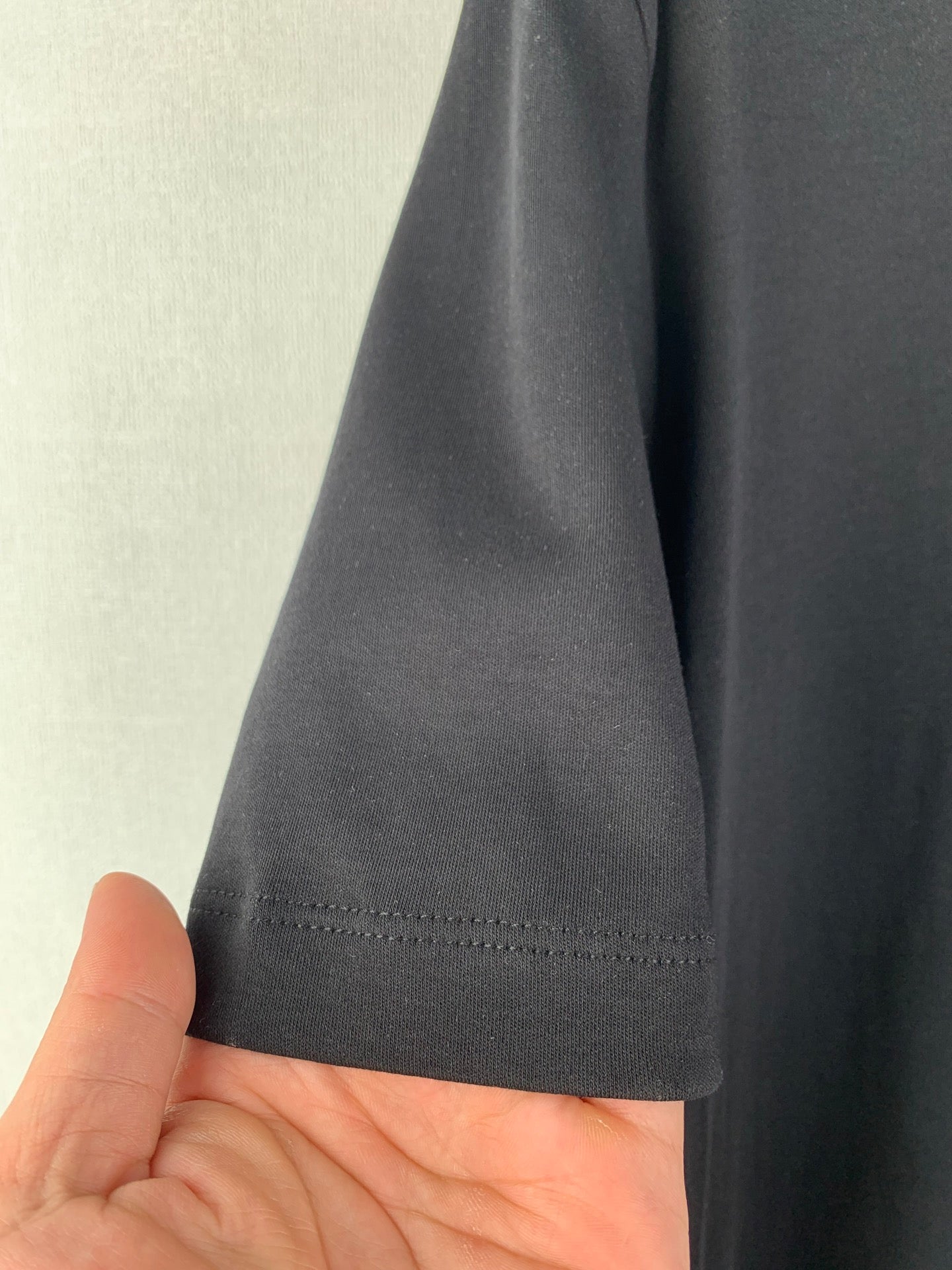 Dark T-shirt hem with visible stitching and short sleeve cuff seam.