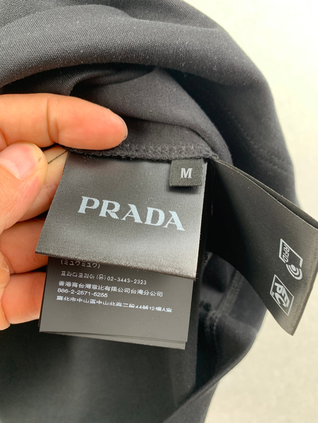 PRADA neck label and size M tag on dark T-shirt collar.
