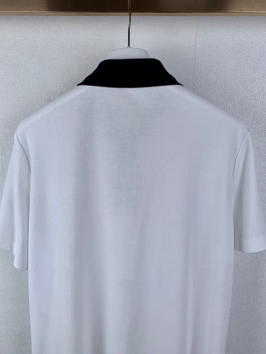 White polo shirt back close-up on hanger
