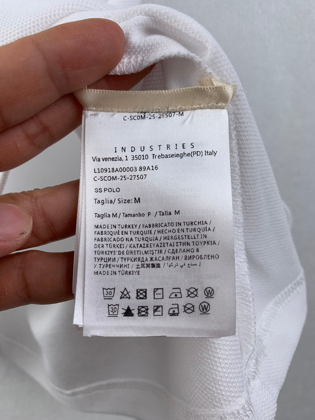 White polo care label and size tag with Industries text