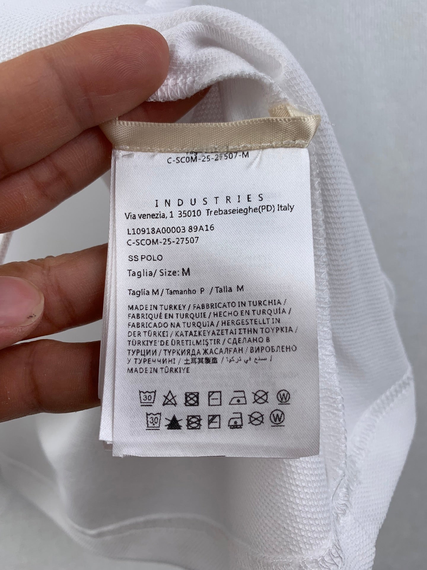 White polo care label and size tag with Industries text