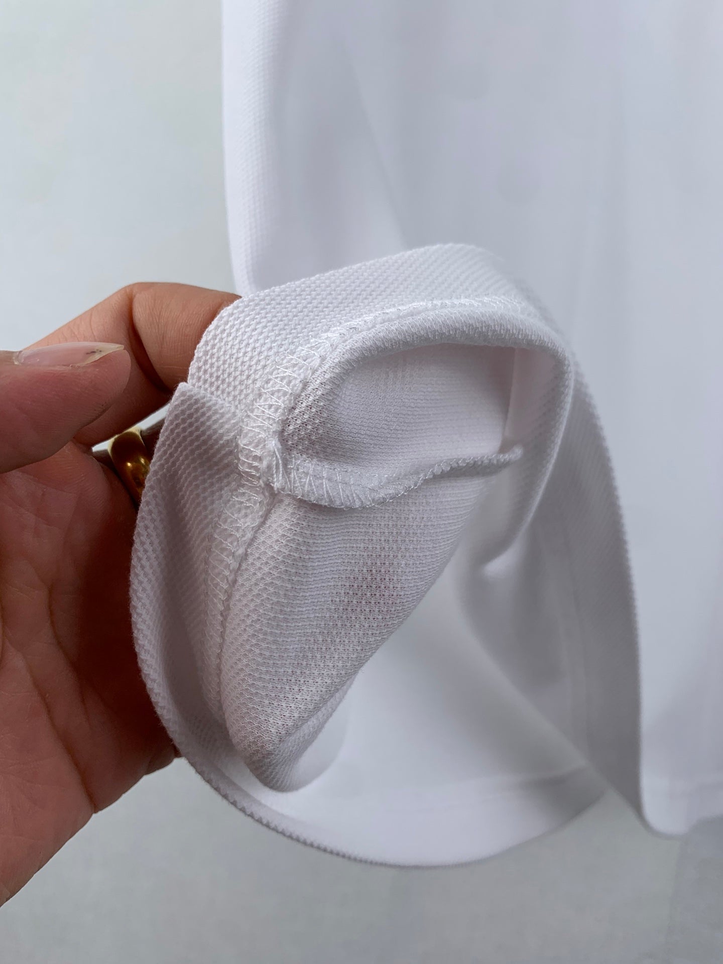 White polo cuff and sleeve seam detail, hand holding