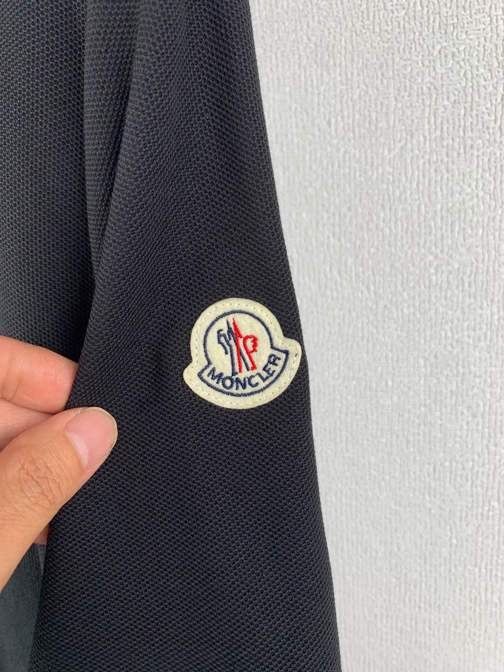 Moncler polo shirt sleeve patch logo on dark fabric