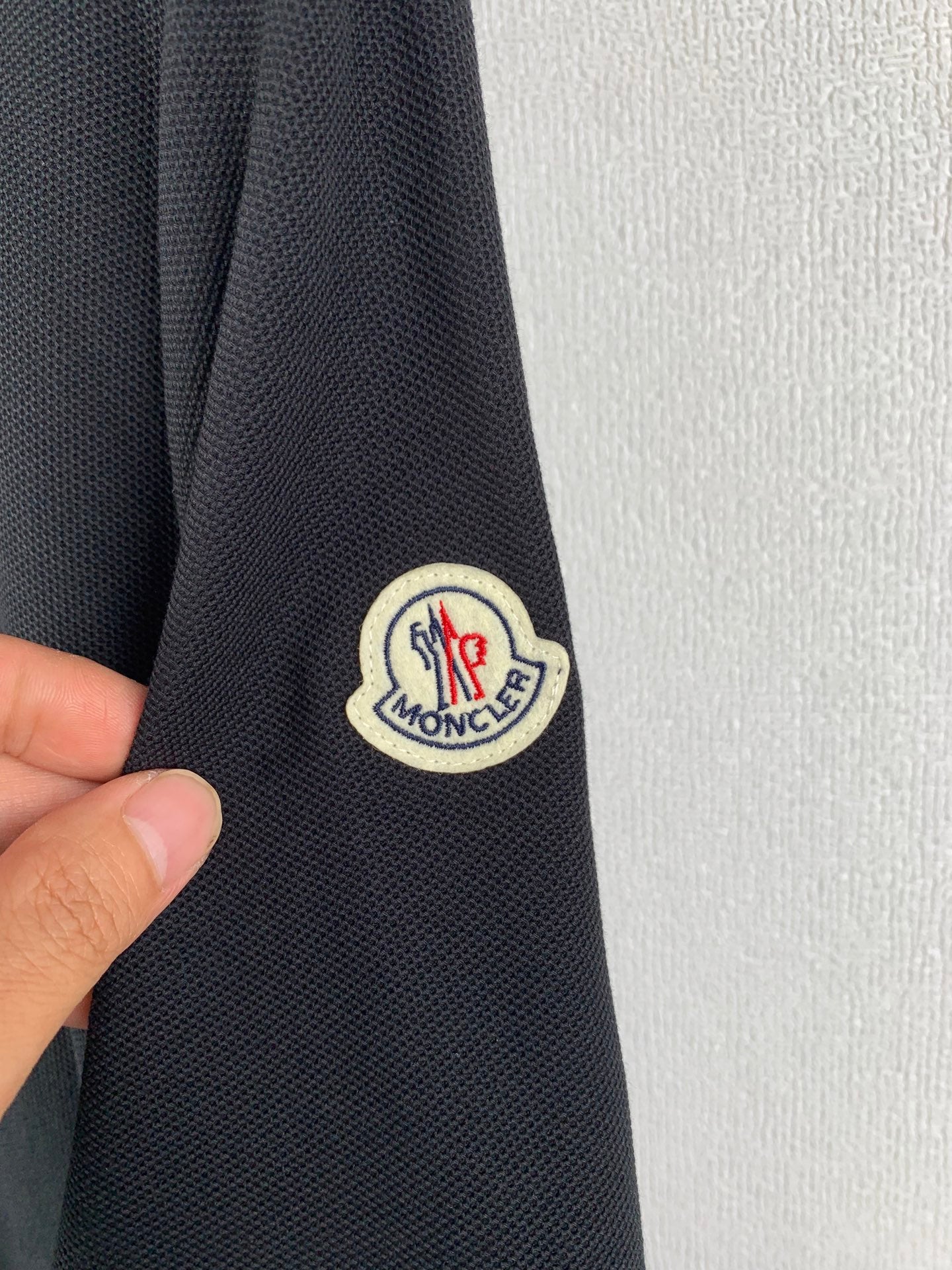Moncler polo shirt sleeve patch logo on dark fabric