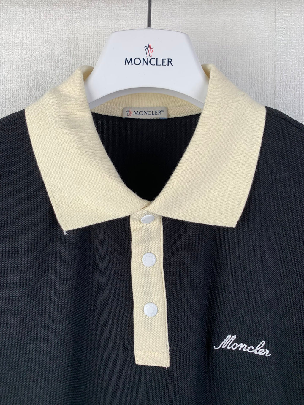 Moncler polo shirt close-up at collar, cream placket buttons and logo