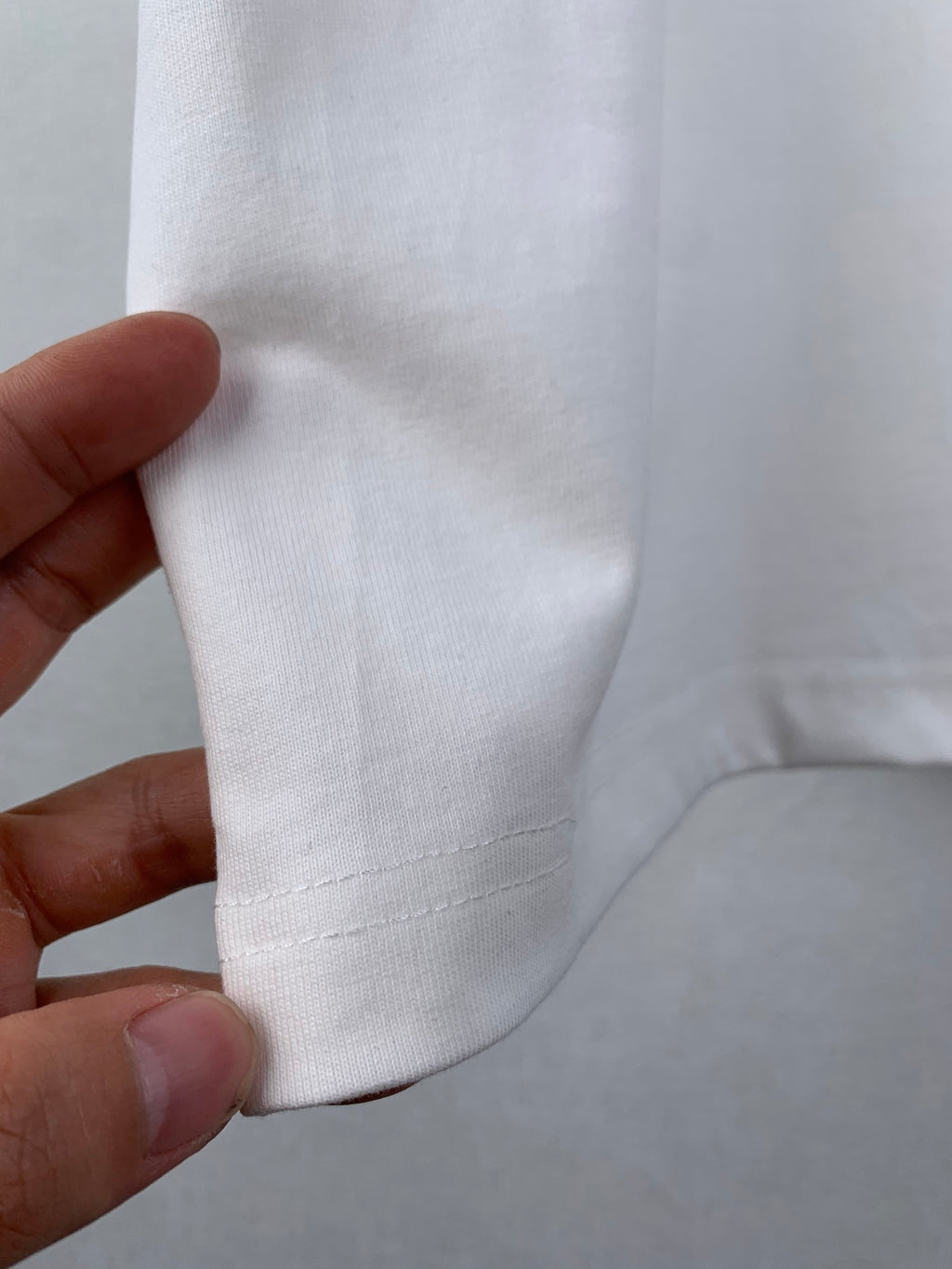 White T-shirt fabric seam detail near side hem, close-up